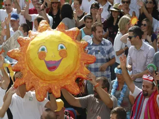 Crowd holding large sun model