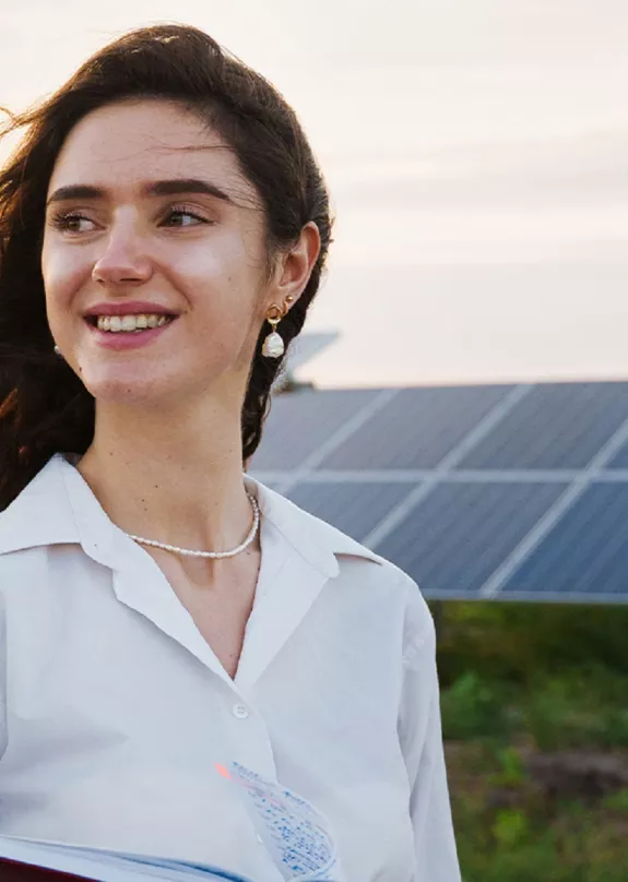 woman investor in front of PV power plant at sunset